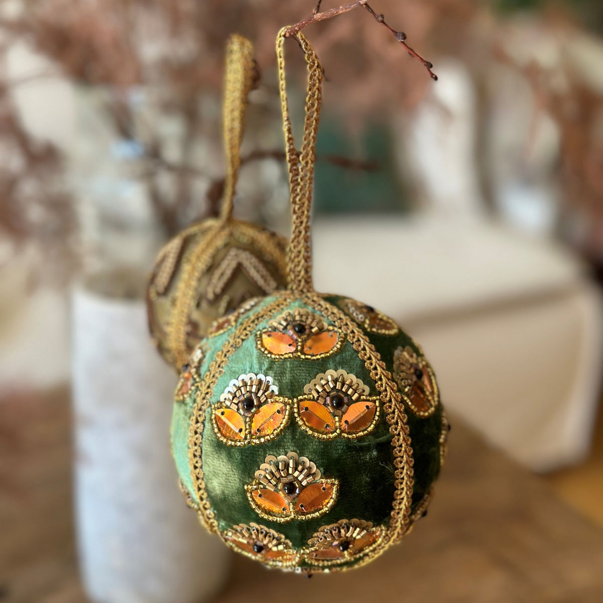 Grøn ornamentkugle med gyldne broderier og palietter, dekoreret med små perler og et bladmønster. Dette ornament bringer en sofistikeret og hyggelig julestemning til hjemmet.